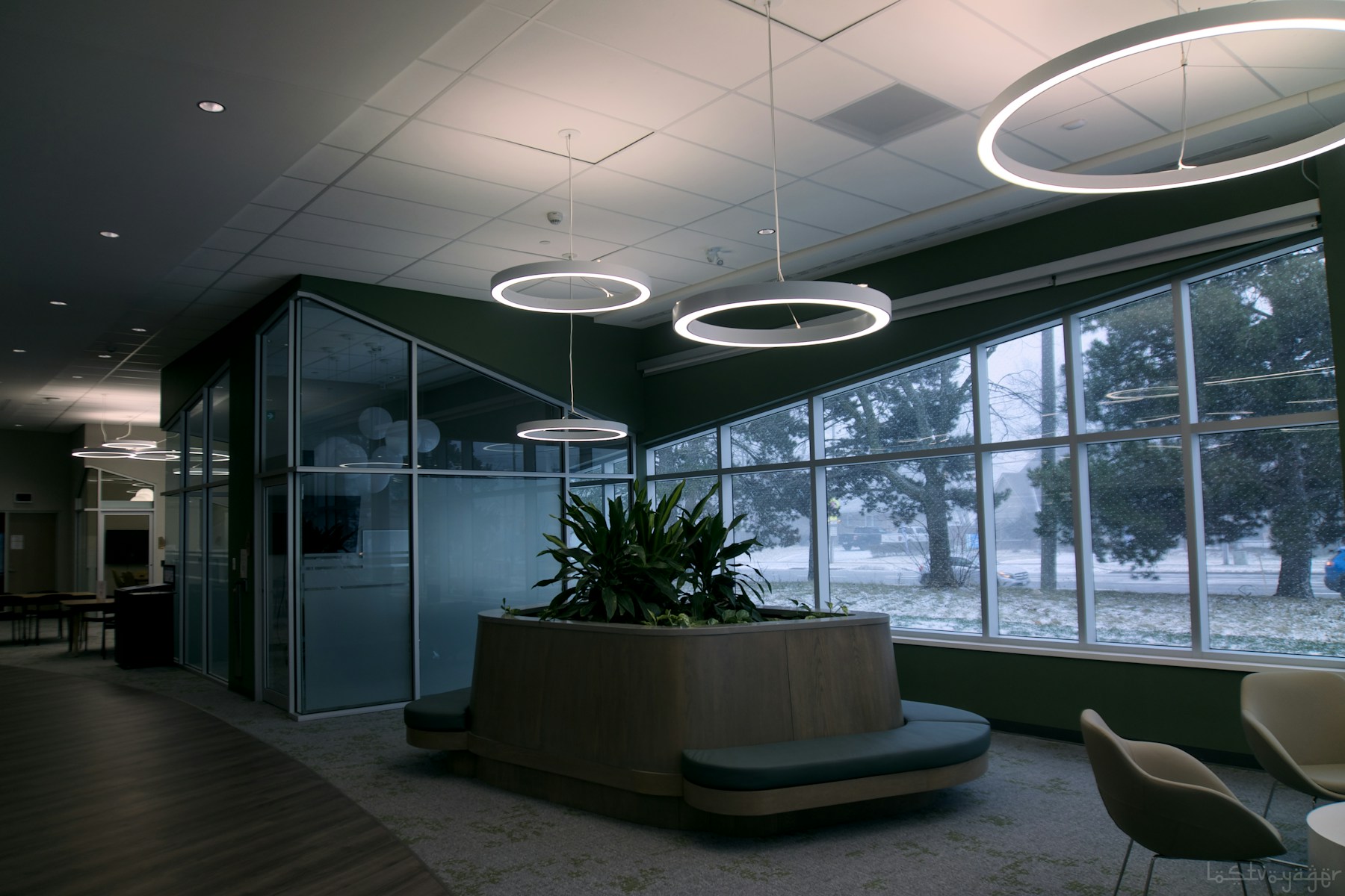 An empty modern office lobby with large windows, plants, and contemporary seating